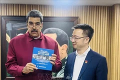 Venezuelan President Nicolas Maduro receives the Spanish edition of "The world's affection for President Ho Chi Minh" from Nguyen Tuong Lam, Secretary of the Ho Chi Minh Communist Youth Union Central Committee. (Photo: Vietnamese Embassy in Venezuela)