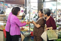 Vendors guide customers in making cashless payments in Ho Chi Minh City. (Photo: phunuonline.com.vn)