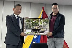 Vietnamese Ambassador to Venezuela Vu Trung My (left) presents a photo of the April 30 victory to a representative of the Antonio Jose de Sucre International Youth Leadership Training School. (Photo courtesy of the Vietnamese Embassy in Venezuela)