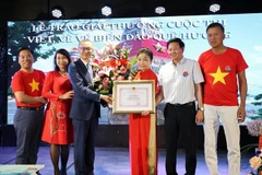 Vietnamese Ambassador to Germany Vu Quang Minh presents a certificate of merit and flowers to Bui Thi Thu Minh, head of the Vietnamese Liaison Committee in Europe "For Vietnam's Seas and Islands", President of the Truong Sa Club in Germany. (Photo: VNA) 