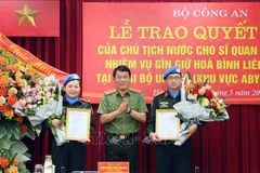 Deputy Minister of Public Security Sen. Lt. Gen. Luong Tam Quang (centre) presents the State President's decisions to the two officers on May 29. (Photo: VNA)